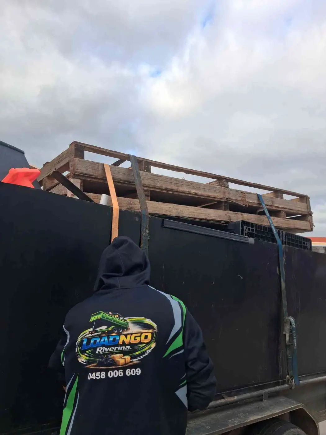A Riverina Load'N'Go crew member in branded workwear strapping a pallet load onto the truck