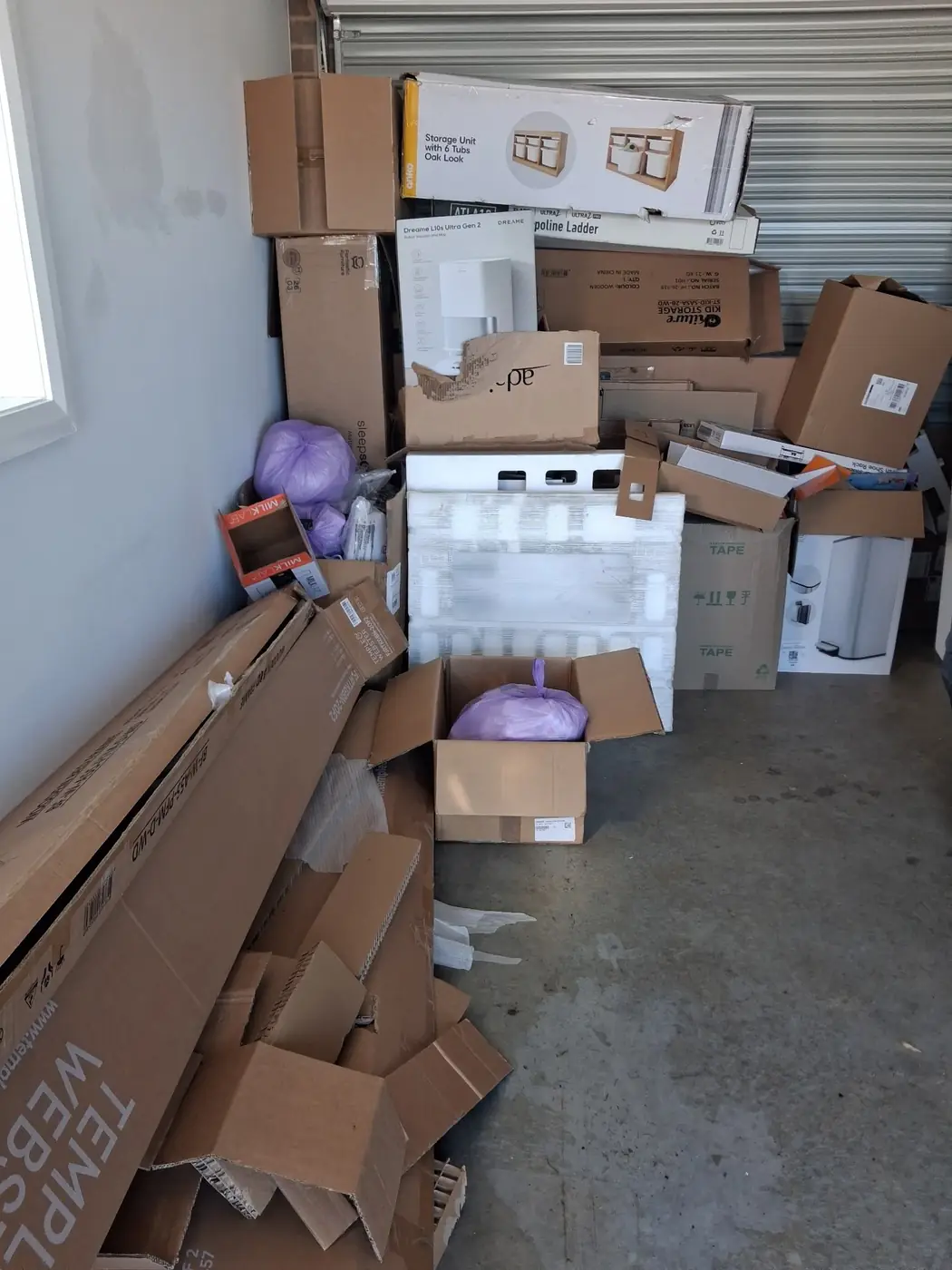 A garage packed wall to wall with cardboard boxes and appliance packaging