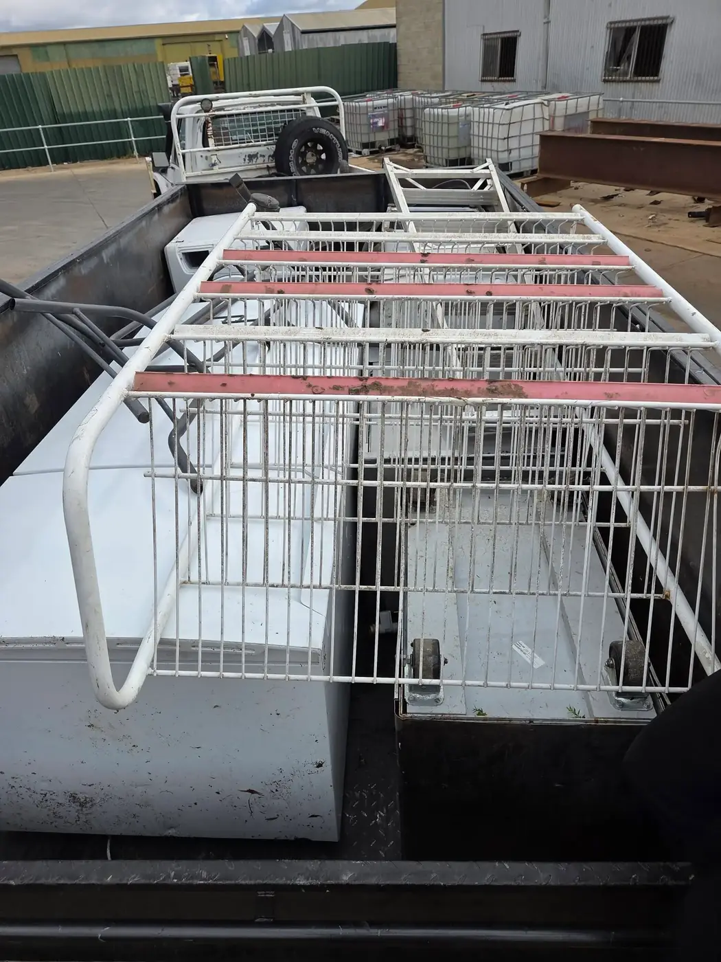 A trailer loaded with metal shelving, cages and old appliances ready to leave site