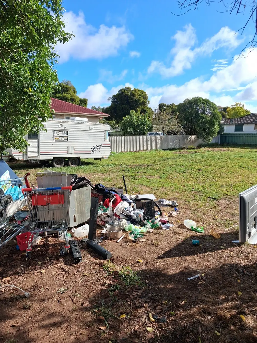 A residential block holding an old caravan and a pile of dumped rubbish before clearing