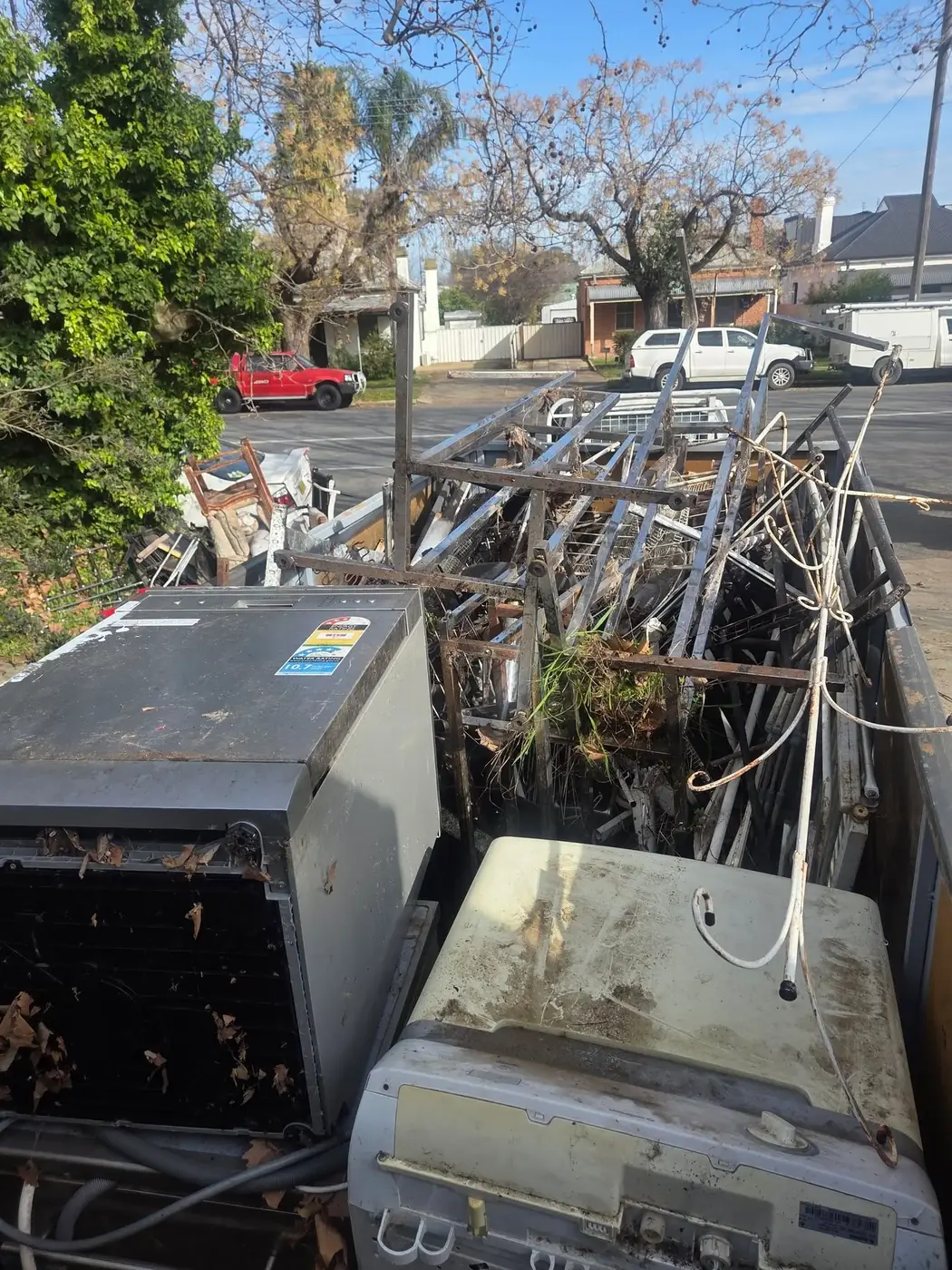 A roadside pile of old air conditioning units and scrap metal fencing waiting to be removed